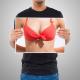 Man holding a photo of a woman's breasts